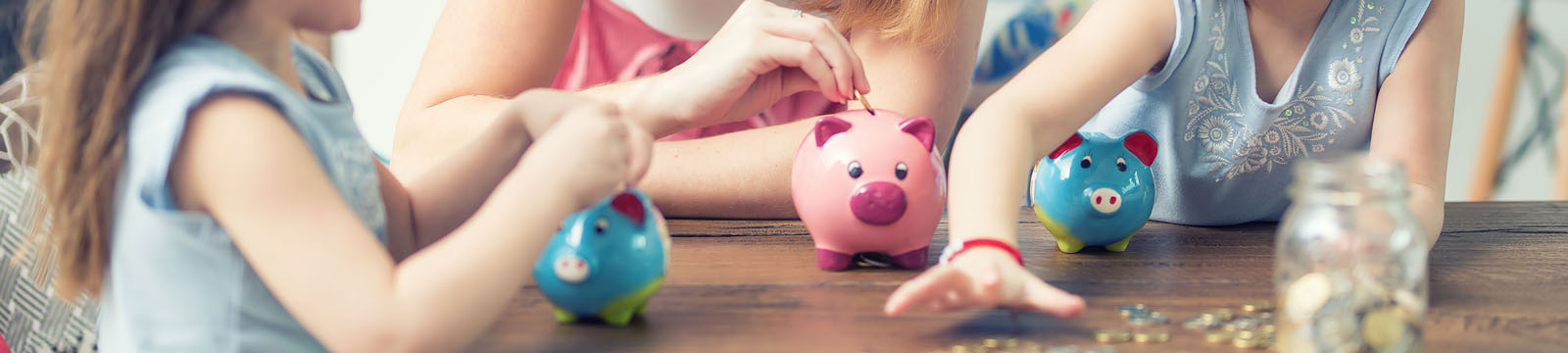 woman and two children's hands putting coins into piggy bank