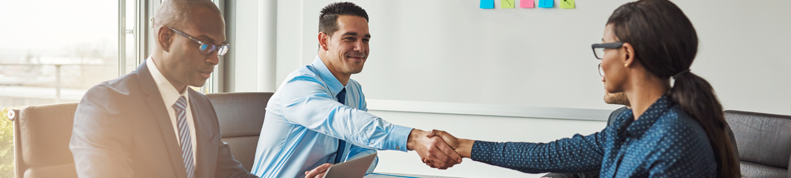 three people in a business office two of them shaking hands